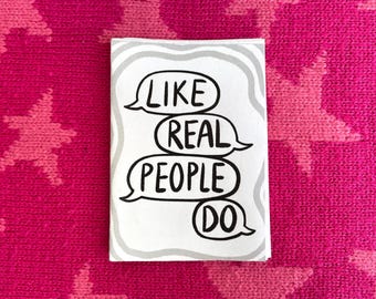 May include: A small, rectangular sticker with the text "LIKE REAL PEOPLE DO" in black speech bubbles. The sticker has a gray border and is set against a vibrant pink background with a star pattern.