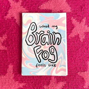Peut inclure: Une petite carte rectangulaire avec les mots "what my Brain Fog feels like" en noir, lettres &agrave; bulles soulign&eacute;es. Le fond pr&eacute;sente un motif tourbillonnant de couleurs pastel rose, bleu et jaune.
