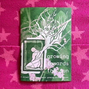 Puede incluir: Una portada de libro con el t&iacute;tulo "growing towards the sun" y una ilustraci&oacute;n de una persona y un &aacute;rbol. La portada es verde con texto blanco y una ilustraci&oacute;n de &aacute;rbol blanco. El fondo es una tela rosa con patrones de estrellas.