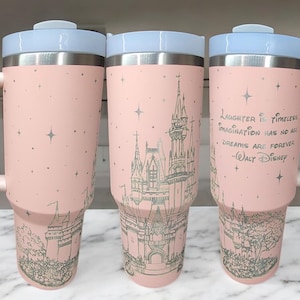 May include: Three pink stainless steel tumblers with a white lid and handle. The tumblers feature a silhouette of a castle with stars and a quote from Walt Disney: "Laughter is timeless, imagination has no age, and dreams are forever."