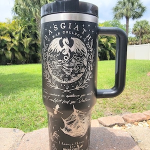 May include: Black stainless steel travel mug with a black handle. The mug features a white design of a dragon, stars, and the text "Basgiath War College". The text "There's nowhere in existence you could go that I wouldn't find you. Violence... I have a thing for Highlords, Wingleaders & Fae Princesses" is also included in the design.