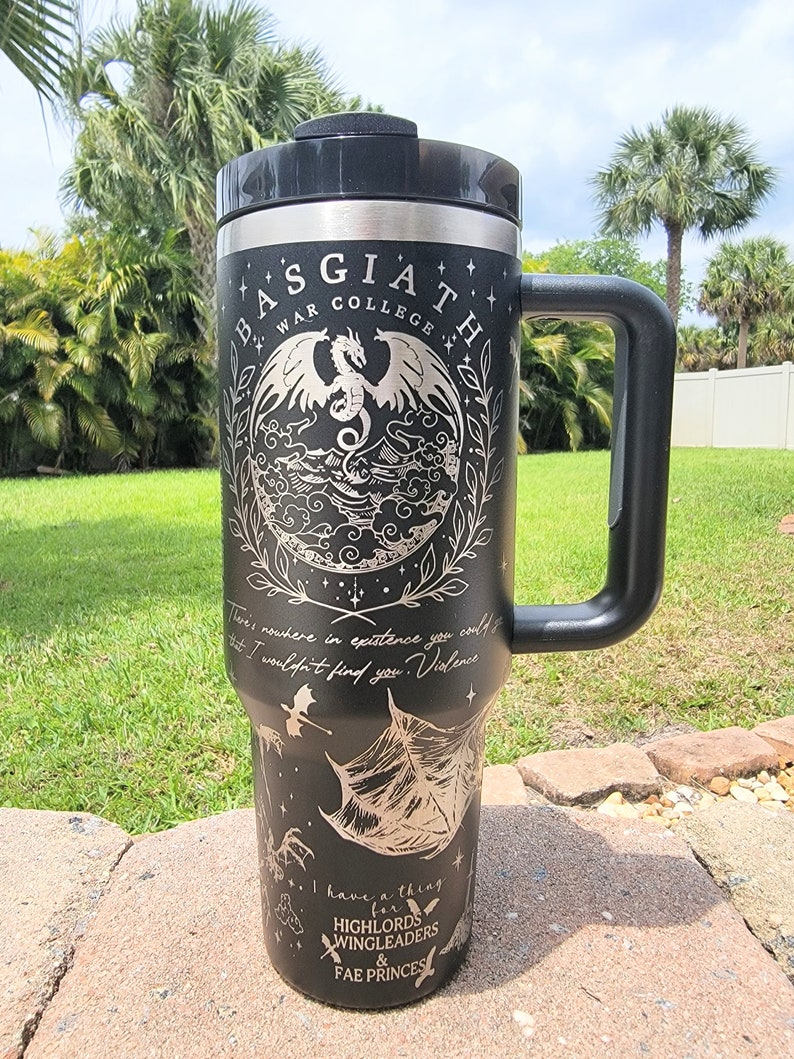 May include: Black stainless steel travel mug with a black handle. The mug features a white design of a dragon, stars, and the text "Basgiath War College". The text "There's nowhere in existence you could go that I wouldn't find you. Violence... I have a thing for Highlords, Wingleaders & Fae Princesses" is also included in the design.