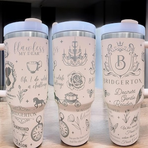 May include: Three stainless steel tumblers with a white powder coat and silver designs. The tumblers feature quotes and images from the Bridgerton series. The first tumbler has a quote about a challenge, the second tumbler has a quote about a rose, and the third tumbler has a quote about a reader.