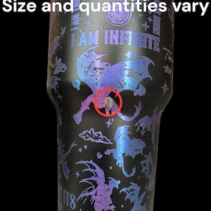 May include: A black stainless steel tumbler with a holographic finish. The tumbler features a design of dragons and the text "I AM INFINITE". The tumbler has a small imperfection in the design. The text "No returns" is visible at the bottom of the image.