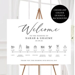 May include: A white wedding welcome sign with black calligraphy font. The sign includes the names Sarah & Graeme, the date 30.06.22, and a timeline of wedding events with icons.