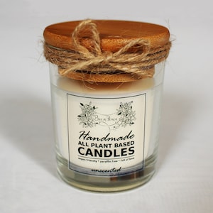 May include: A glass jar candle with a white label that reads "Handmade All Plant Based Candles" and "vegan friendly * paraffin free * full of love" and "unscented". The jar has a wooden lid with a twine bow.