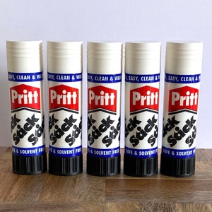 Puede incluir: Cinco barras de pegamento blanco con etiquetas azules y rojas. Las etiquetas dicen "Pritt Stick" y "Easy, Clean & Was, Safe & Solvent Free".