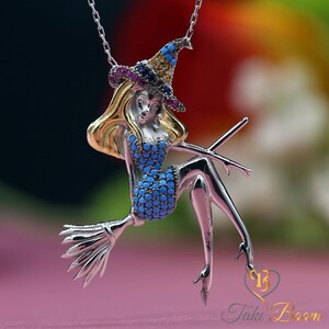 May include: Silver necklace with a charm of a witch riding a broomstick. The witch is wearing a blue dress with turquoise gems and a pointed hat with yellow, pink, and blue gems.