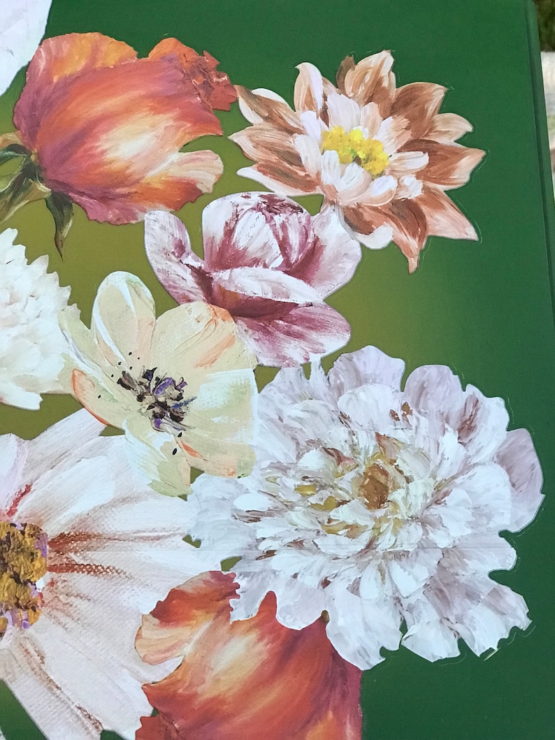 Op de afbeelding: Een close-up van een geschilderd bloemstuk met verschillende bloemen in tinten wit, roze, oranje en bruin. De bloemen zijn geschilderd op een groene achtergrond.