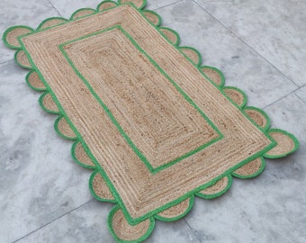 Könnte beinhalten: Ein rechteckiger Jute-Teppich mit grünem, gewelltem Rand. Der Teppich hat eine gewebte Struktur und besteht aus Naturfasern.