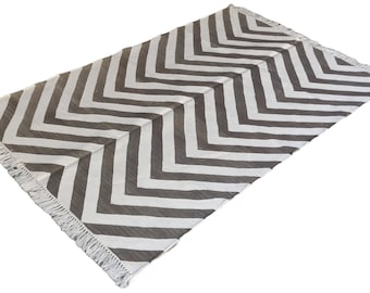 Puede incluir: Una alfombra de chevron blanca y gris con flecos en todos los lados.