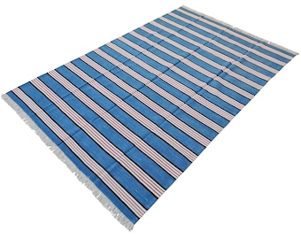 May include: Blue and white striped rug with pink accents. The rug has a fringe border.