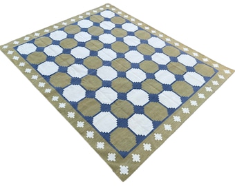 May include: A large, rectangular rug with a geometric pattern. The rug has a white background with a grid of blue and green squares.