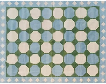May include: A blue and white rug with a geometric pattern of green circles. The rug has a white border with a blue and white pattern.