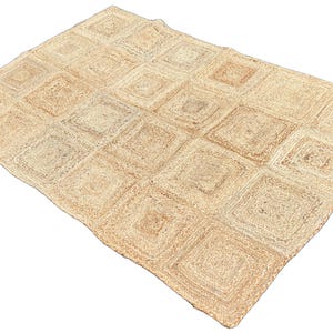 Könnte beinhalten: Ein rechteckiger Jute-Teppich mit einem sich wiederholenden quadratischen Muster. Der Teppich besteht aus Naturfasern in Beige- und Brauntönen. Die Quadrate sind in einem gitterartigen Design angeordnet.