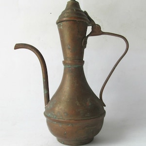 May include: A vintage copper teapot with a bulbous body, a long spout, and a hinged lid with a finial. The teapot has a patina of age and is in good condition.