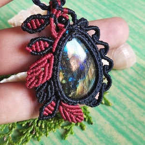 May include: A black and red macrame necklace with a large iridescent labradorite gemstone pendant.