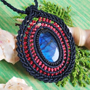 May include: A black and red macrame necklace with a blue labradorite gemstone pendant.