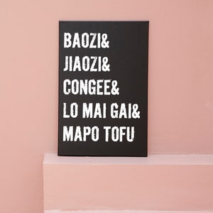 May include: A black sign with white text listing various Chinese dishes: Baozi, Jiaozi, Congee, Lo Mai Gai, and Mapo Tofu.