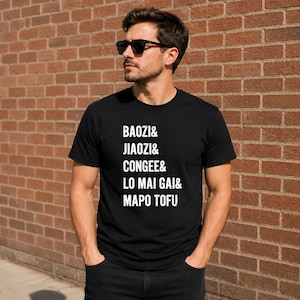 May include: A black short-sleeved t-shirt featuring white text printed on the chest that reads BAOZI& JIAOZI& CONGEE& LO MAI GAI& MAPO TOFU. The shirt has a crew neckline and is made of a solid black fabric with bold, sans-serif white lettering.