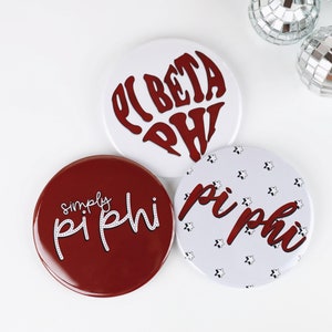 May include: Three round white and red buttons with the text "Pi Beta Phi" in a heart shape, "simply Pi Phi" in white script, and "Pi Phi" in red script with white stars.