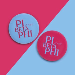 May include: Two round buttons with the text "Pi Beta Phi est 1867" in pink lettering on a blue and pink background.
