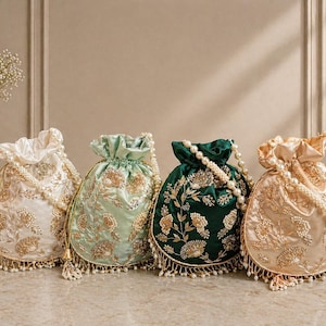 May include: Four embroidered drawstring bags in cream, mint green, emerald green, and gold. Each bag features floral embroidery, pearl accents, and a beaded tassel fringe. The bags are arranged in a row on a light-colored surface.