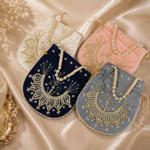 May include: Four small drawstring pouches in white, pink, navy blue, and gray. Each pouch features intricate gold thread embroidery, scattered white beads, and a decorative pearl-beaded handle. The bags have a rounded bottom and a cinched top.