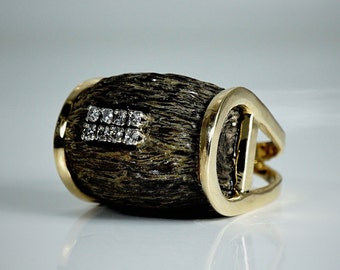 May include: A gold ring with a dark brown wooden band and a row of small diamonds set in the band.