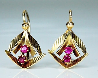 May include: A pair of gold earrings with a geometric design and two ruby stones.