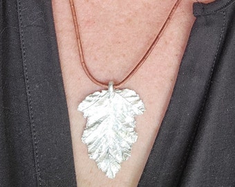 Bold fine silver maple leaf pendant on brown leather cord.