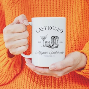 May include: White ceramic mug with a black design that says "Last Rodeo Est. 2024" with a drawing of cowboy boots and a cocktail glass. The text "Morgan's Bachelorette Nashville, TN" is also on the mug.