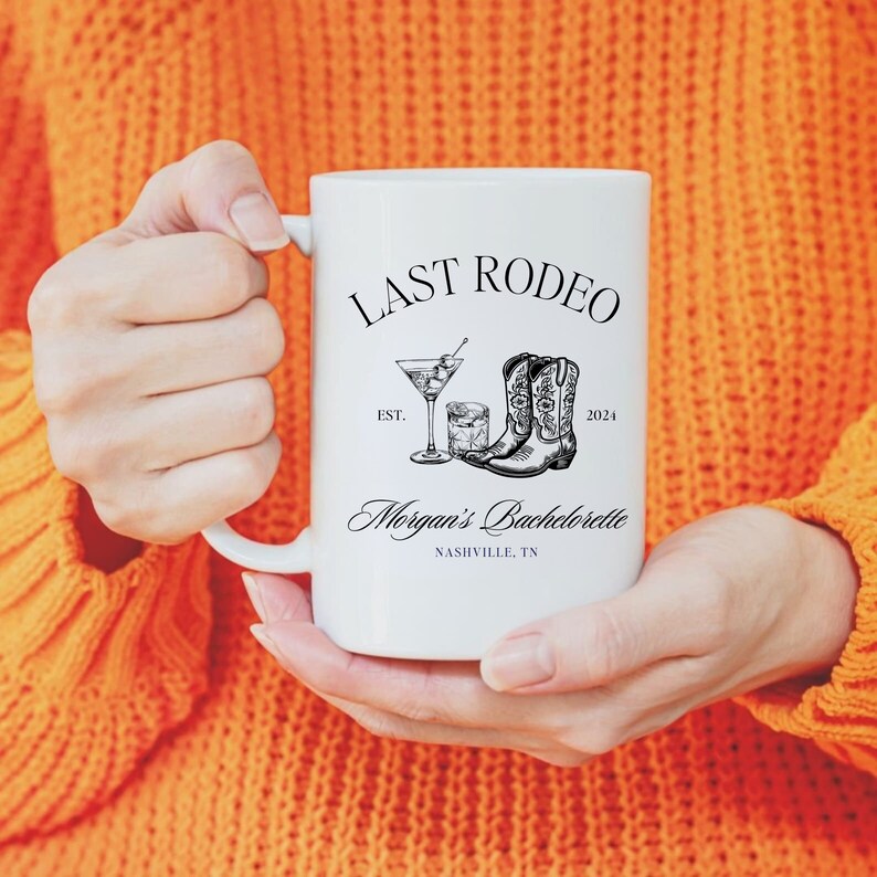 May include: White ceramic mug with a black design that says "Last Rodeo Est. 2024" with a drawing of cowboy boots and a cocktail glass. The text "Morgan's Bachelorette Nashville, TN" is also on the mug.