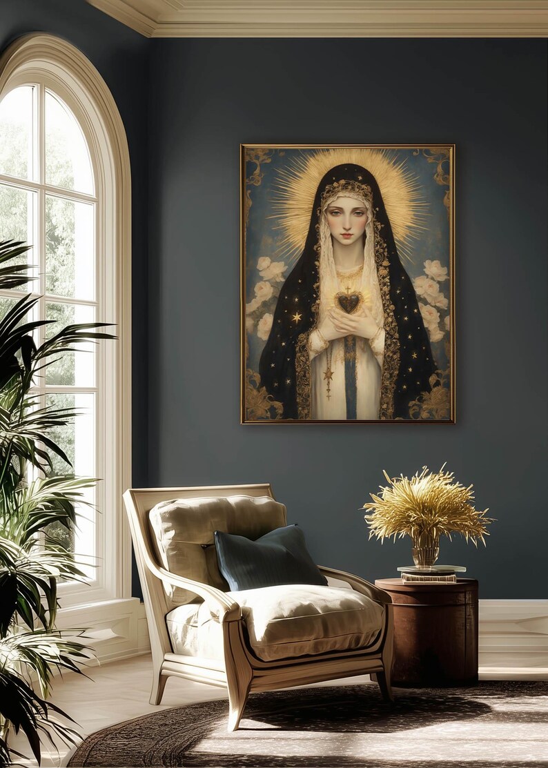 May include: A framed religious portrait depicts a woman with a halo, wearing a black veil adorned with gold stars. She holds a heart, set against a blue background with white flowers. The artwork hangs in a room with a chair and a side table.