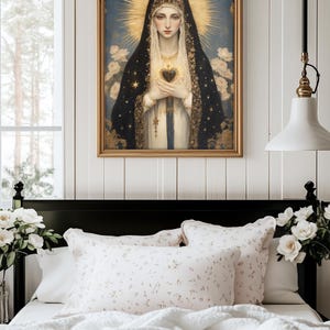 May include: A framed religious portrait depicts a woman with a golden halo, wearing a black veil with gold stars, holding a heart. The artwork hangs above a bed with floral pillows and a white comforter, creating a serene bedroom scene.