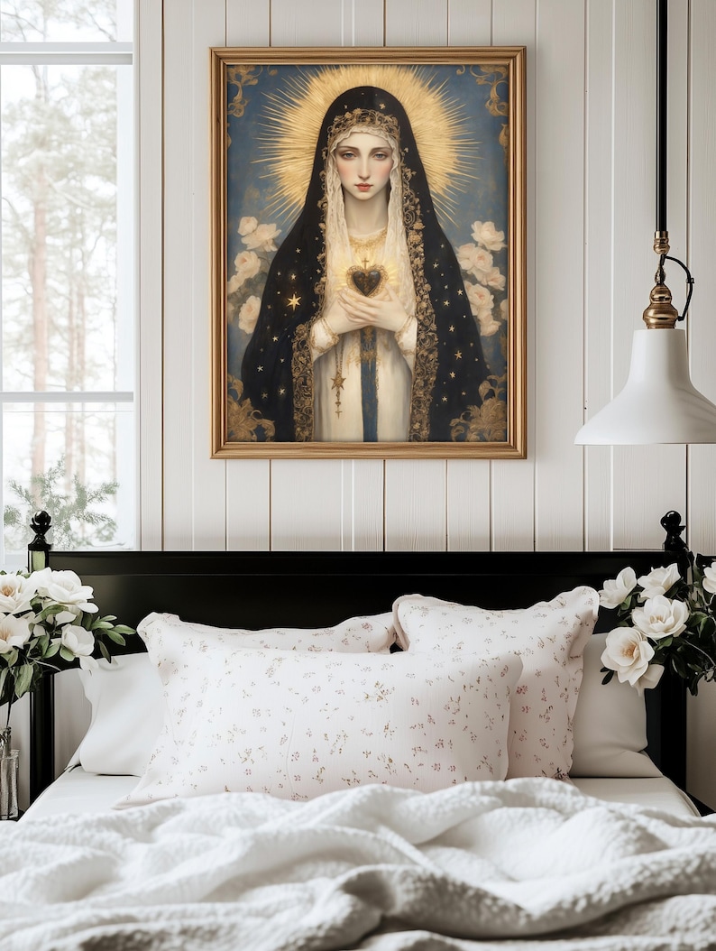 May include: A framed religious portrait depicts a woman with a golden halo, wearing a black veil with gold stars, holding a heart. The artwork hangs above a bed with floral pillows and a white comforter, creating a serene bedroom scene.