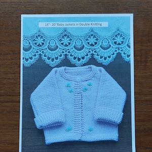 May include: A pink knitted baby jacket with blue flower embroidery. The jacket is laid out on a wooden surface with a blue lace trim above it. The text "16" - 20" Baby Jackets in Double Knitting" is printed at the top of the image.