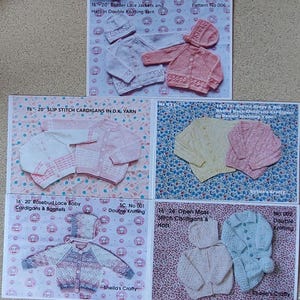 May include: A collection of five knitting pattern leaflets featuring baby cardigans and bonnets in various colours including white, pink, yellow, and blue. Each leaflet displays text such as 16-20 inch Border Lace Jackets and Hats, Slip Stitch Cardigans, and Rosebud Lace.
