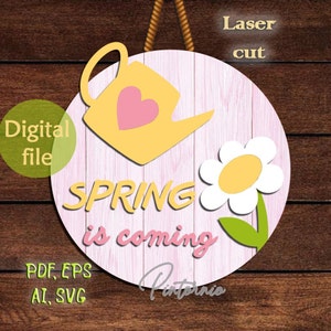 Könnte beinhalten: Ein rundes Schild aus rosa Holz mit dem Text "SPRING is coming" in gelben Buchstaben. Eine gelbe Gießkanne mit einem rosa Herzen und eine weiße Margerite mit gelbem Zentrum befinden sich auf dem Schild.
