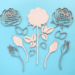 May include: A set of wooden rose cutouts in various sizes and shapes, including a large rose with leaves and stems, smaller roses, and buds. The cutouts are on a light blue background.