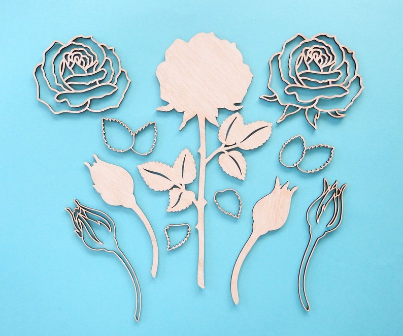 May include: A set of wooden rose cutouts in various sizes and shapes, including a large rose with leaves and stems, smaller roses, and buds. The cutouts are on a light blue background.
