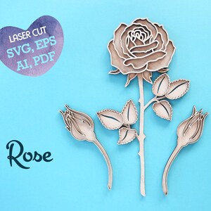May include: Laser cut rose design with a single rose, three buds, and leaves. The design is made of wood and is available in SVG, EPS, AI, and PDF formats. The text "Laser Cut SVG, EPS AI, PDF" is in a heart shape and the text "Rose" is below the design.
