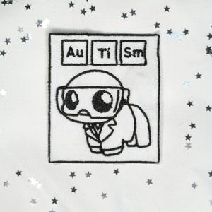 Peut inclure: Écusson brodé noir et blanc représentant un personnage de dessin animé avec des lunettes et une blouse de laboratoire, avec les lettres "Au Ti Sm" au-dessus, épelant "Autisme".