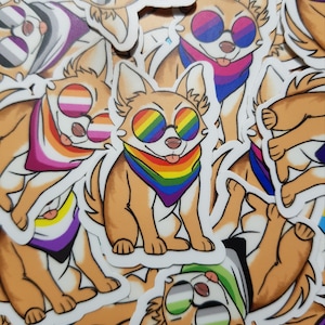 Peut inclure: Un ensemble d'autocollants colorés représentant des chiens de dessin animé portant des bandanas et des lunettes de soleil aux couleurs de l'arc-en-ciel, bisexuels et non genrés. Les autocollants sont imprimés sur du papier blanc et ont une finition brillante.
