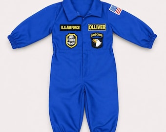 May include: A bright blue long-sleeve jumpsuit featuring a collar, elastic cuffs, and various patches. Patches include U.S. AIR FORCE, OLLIVER, an Air Force shield, an Airborne eagle emblem, and a small American flag on the left shoulder.