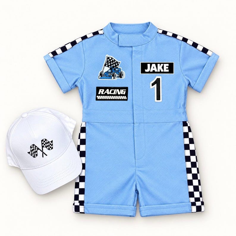 May include: A light blue short-sleeve romper with black and white checkered trim on the sleeves and sides. The romper features a race car graphic, the text "RACING", the name "JAKE", and the number "1". A white baseball cap with two checkered flags.
