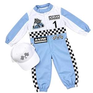 Puede incluir: Un mono de carreras azul claro y blanco con un patrón de cuadros negros y blancos, el nombre ADRIAN, el número 1 y gráficos de banderas de carreras. El mono se acompaña de una gorra de béisbol blanca a juego con un emblema de bandera a cuadros.