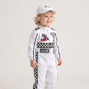 May include: A white racing jumpsuit featuring a black and white checkered pattern along the torso and legs, with patches displaying a red race car, the name RYAN, the number 2, and the word RACING. Includes a matching white baseball cap with a flag.