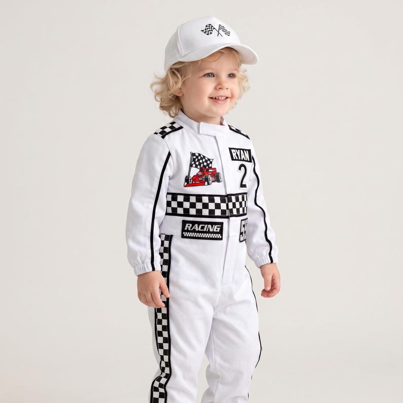 May include: A white racing jumpsuit featuring a black and white checkered pattern along the torso and legs, with patches displaying a red race car, the name RYAN, the number 2, and the word RACING. Includes a matching white baseball cap with a flag.