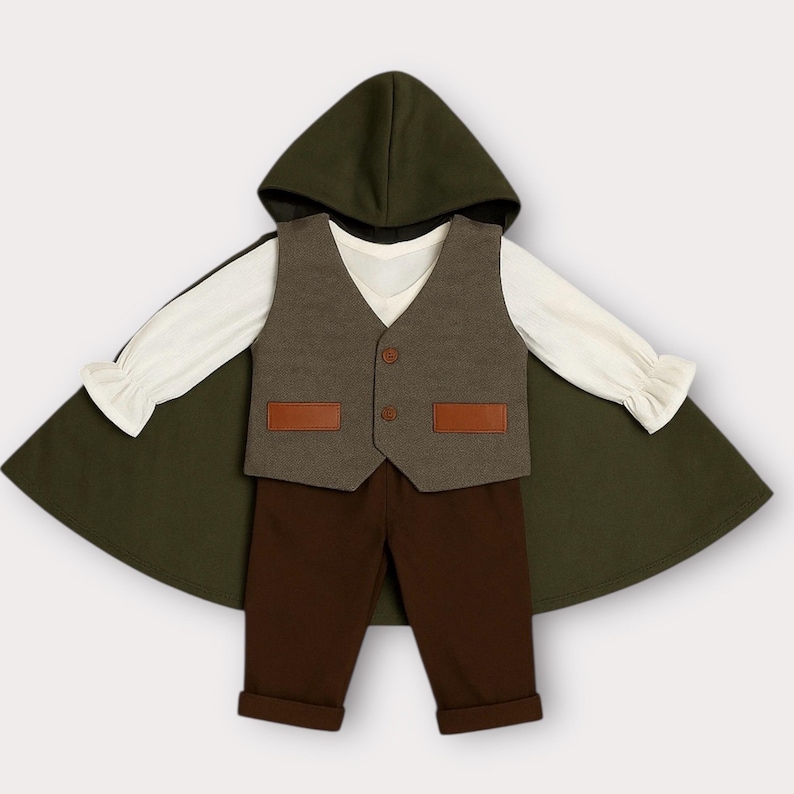 May include: A set consisting of a dark olive green hooded cloak, a cream-colored long-sleeve shirt with ruffled cuffs, a grey vest with two brown rectangular pockets and two buttons, and solid dark brown trousers with cuffed hems.